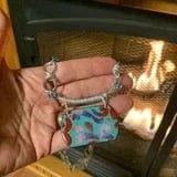 Hand holding colorful necklace near fireplace.
