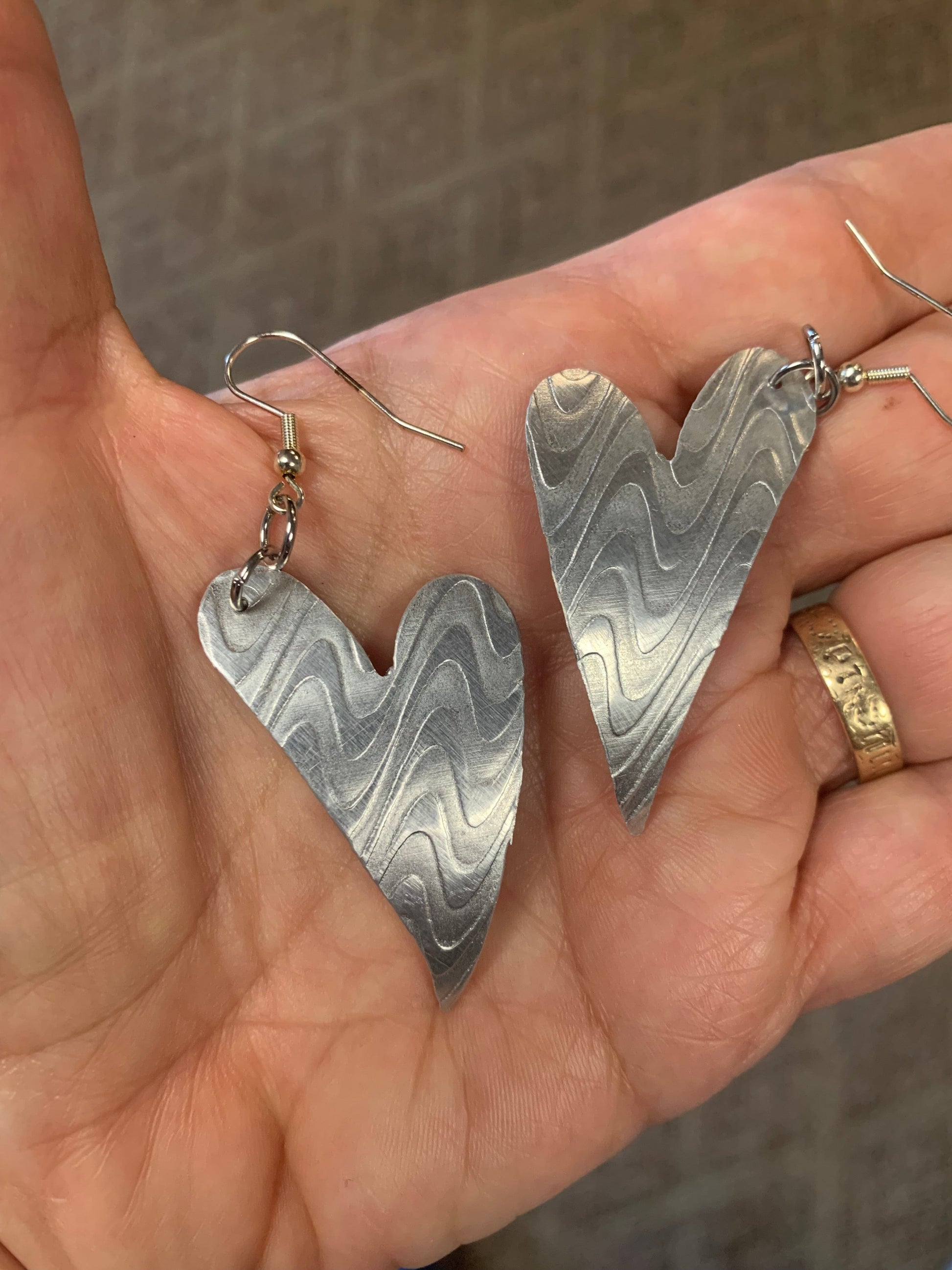 Wonky heart earrings held in hand