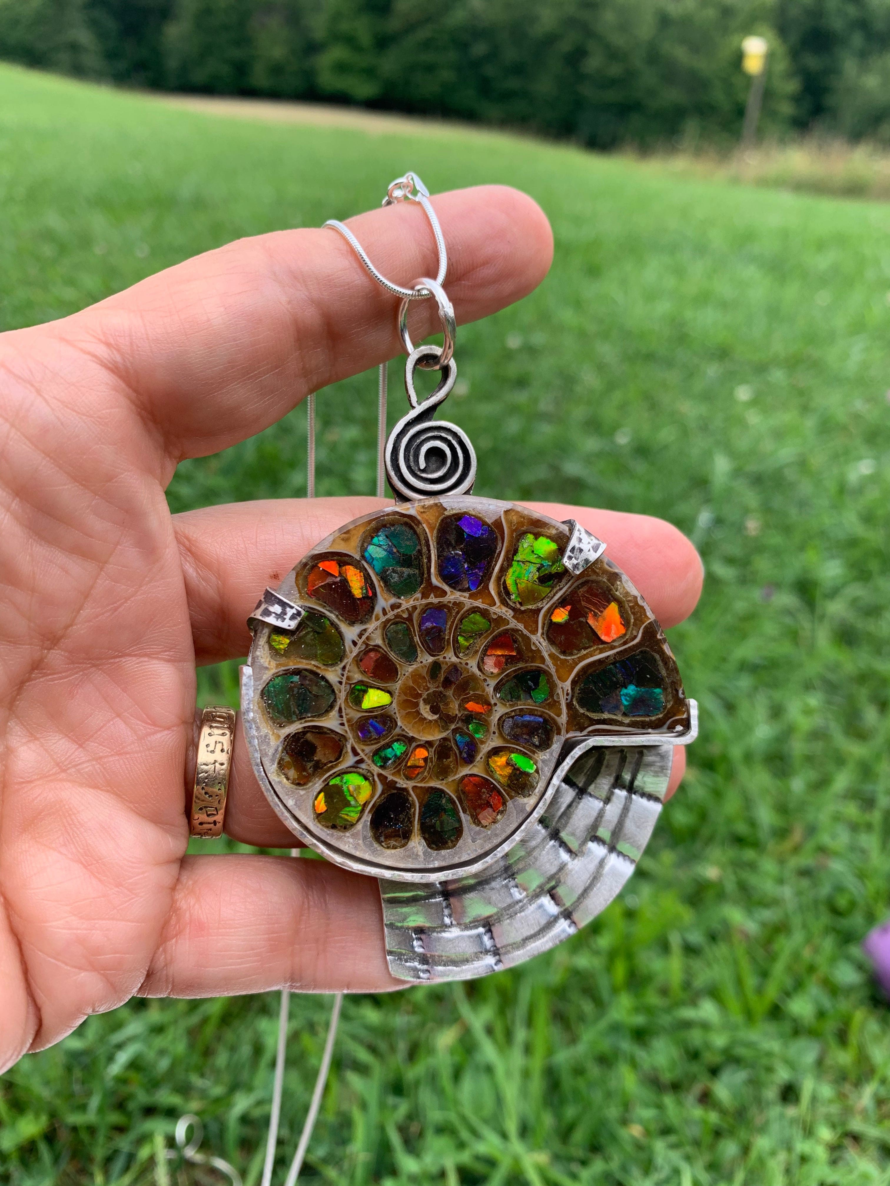 Hand holding an Ammonite Ammolite pendant necklace