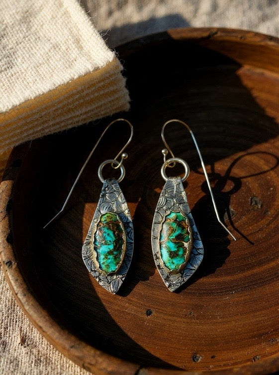Pair of silver and turquoise earrings on a wooden surface
