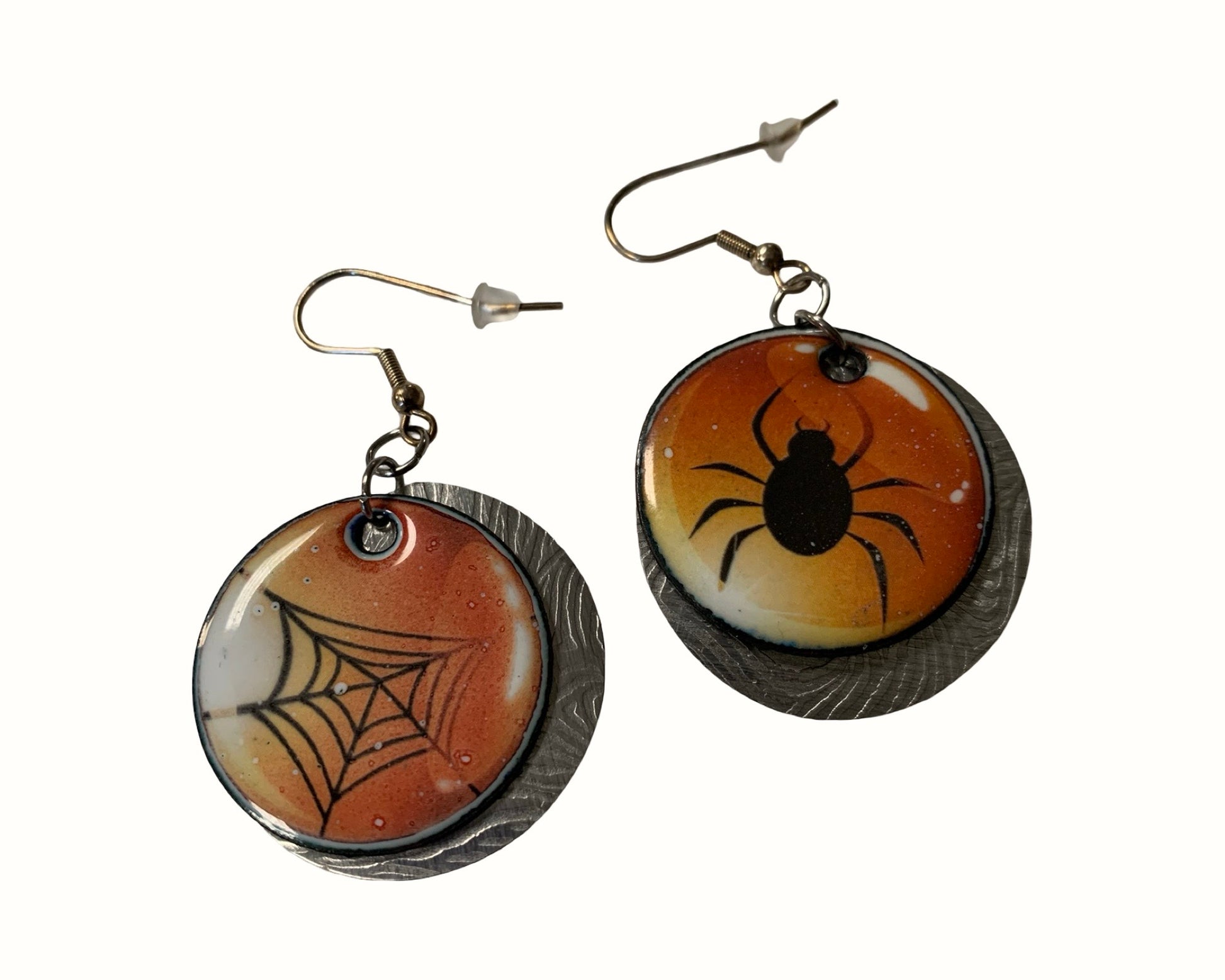 Pair of earrings with spider and web design on a white background