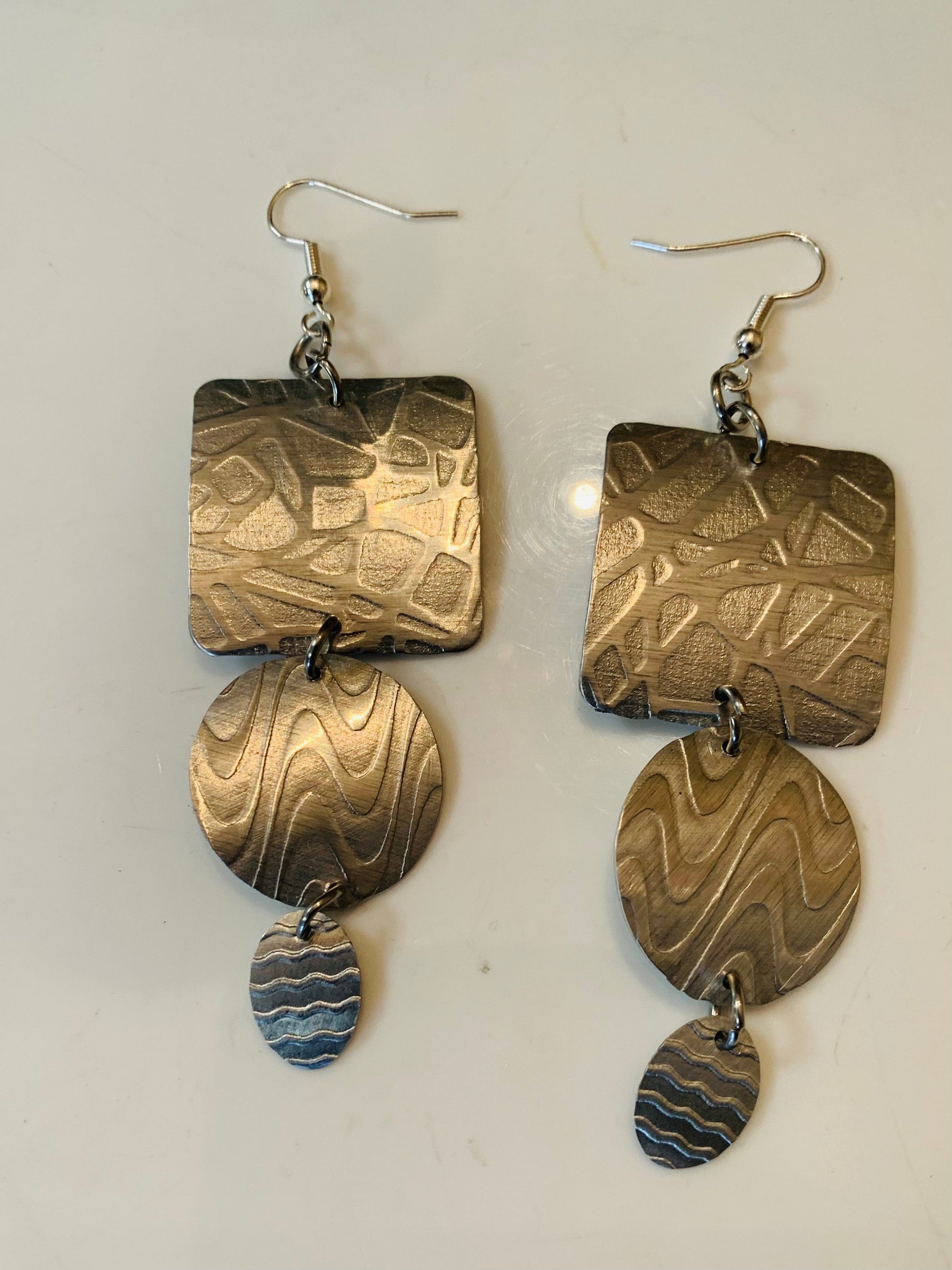 Three-piece square earrings with textured metal design.