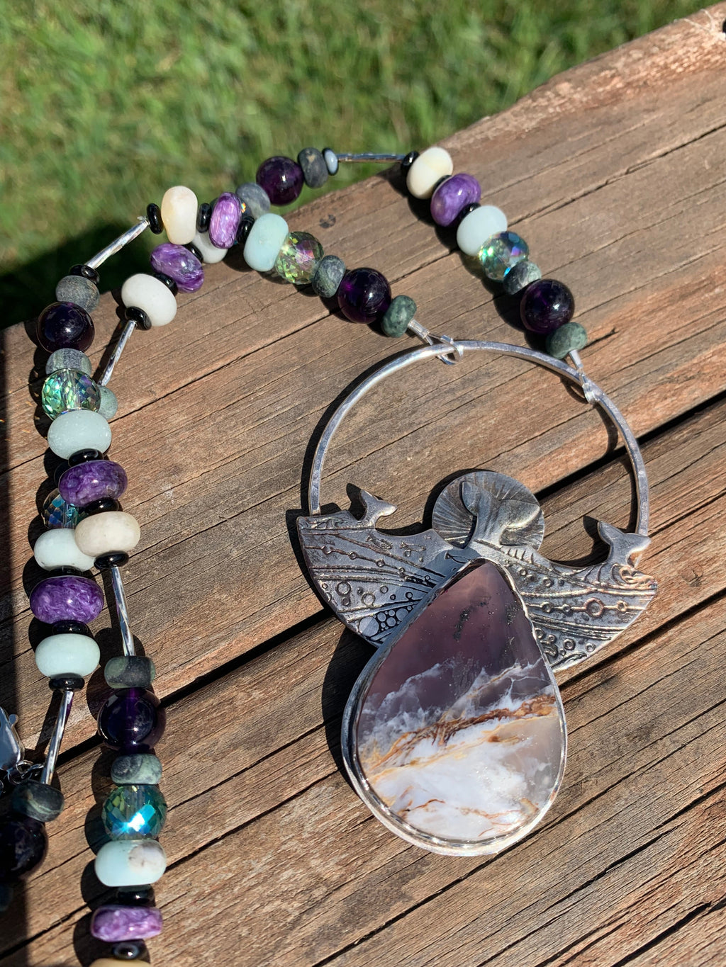 Necklace with beaded chain and large silver pendant on wooden surface