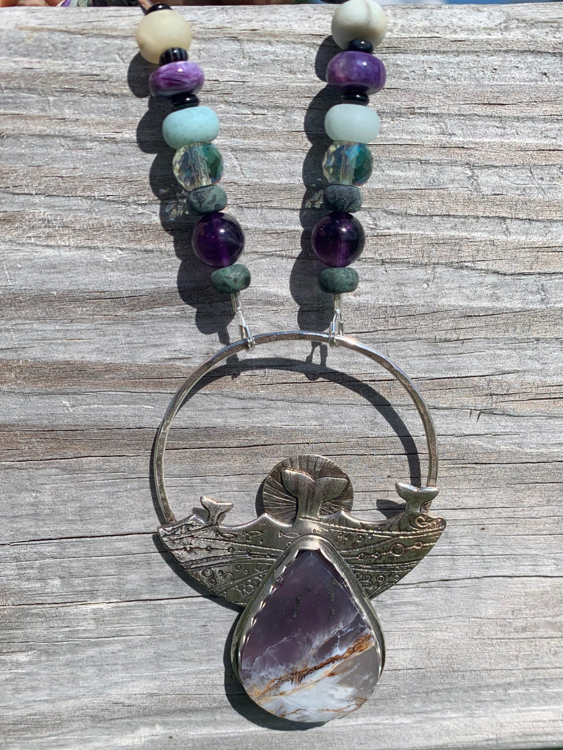 Necklace with beads and a large purple stone pendant on a wooden surface