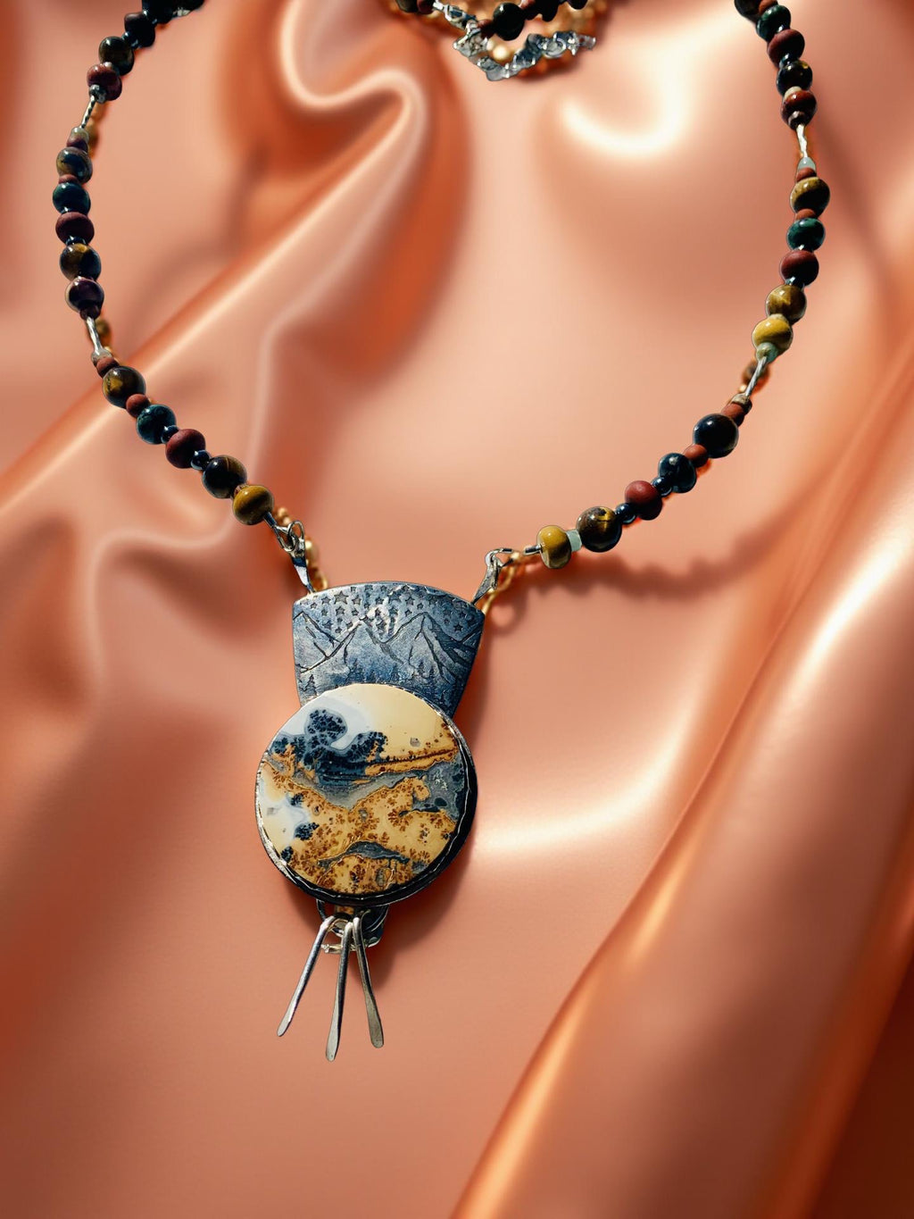 Necklace with a pendant on a peach-colored fabric background