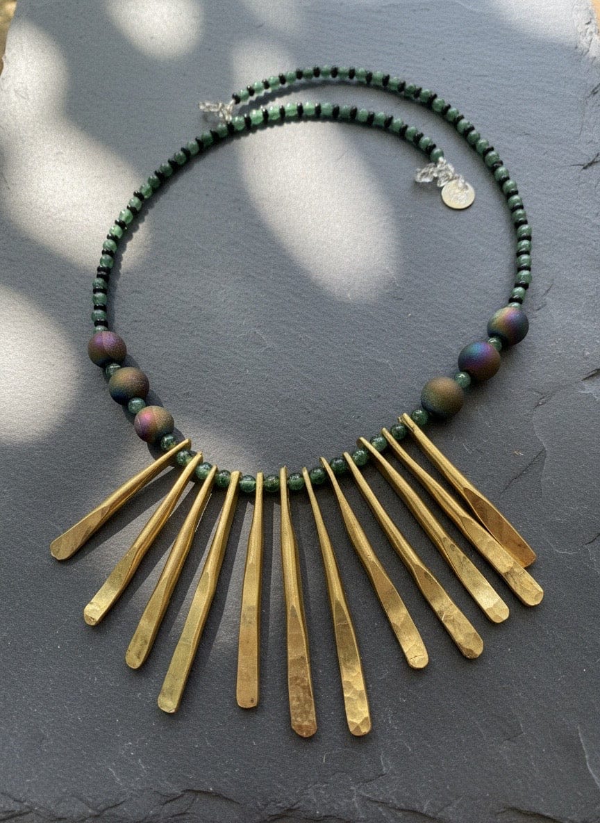 Necklace wit Brass fringe and green beads on a dark surface