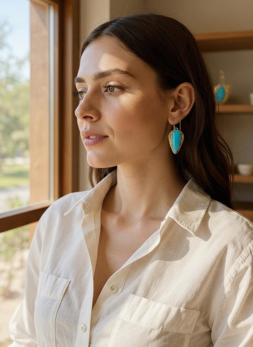 Woman wearing turquoise earrings indoors with a window in the background