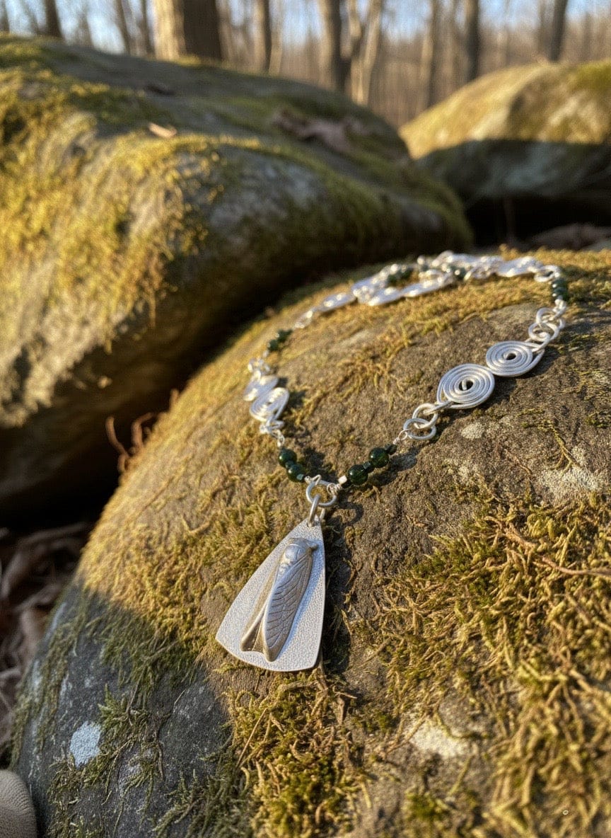 Aluminum necklace with a pendant on a mossy rock in a forest setting