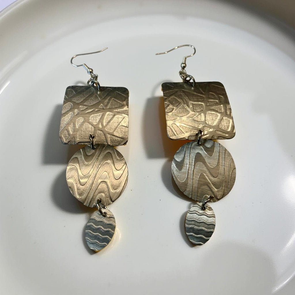 Pair of aluminum silver earrings on a white plate
