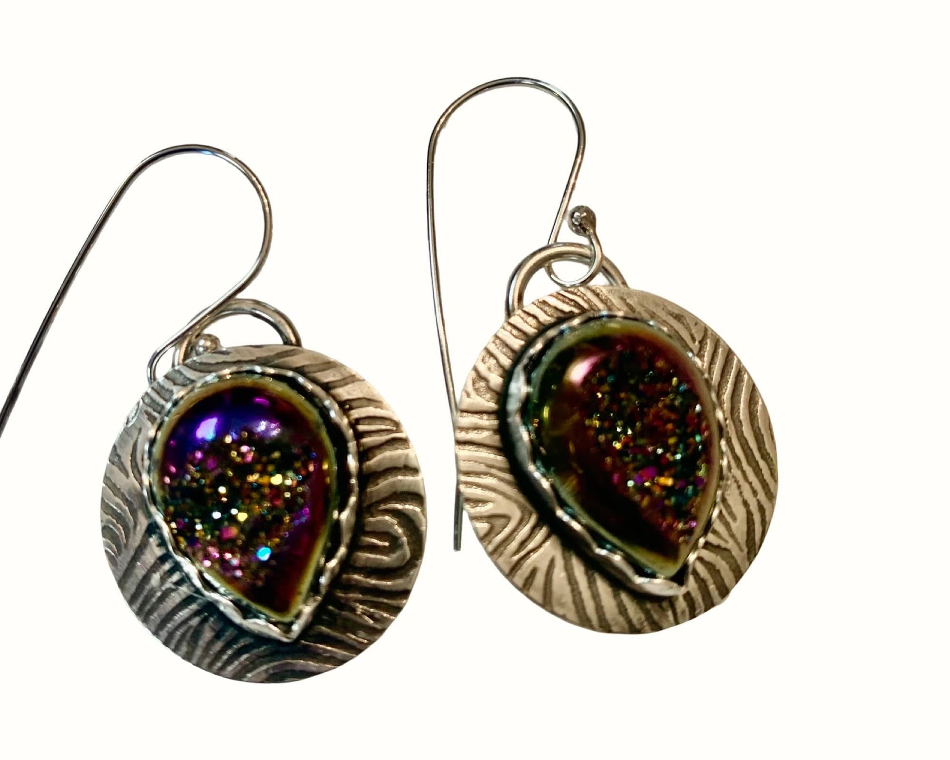 Pair of earrings with metallic sheen and textured design on a white background