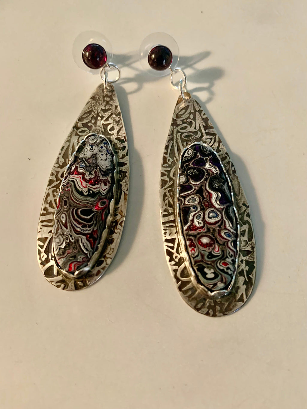 Pair of teardrop-shaped earrings with patterned fordite inlay.