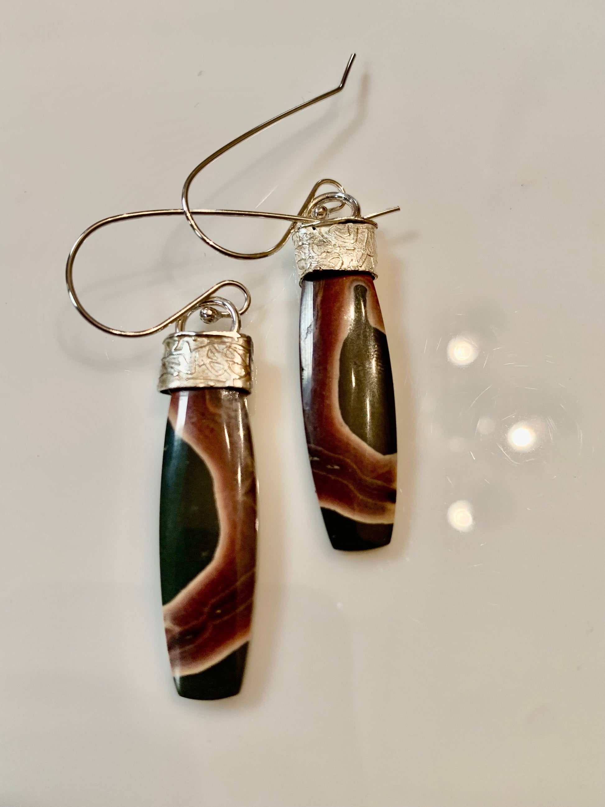 Pair of earrings with brown and green stone design on a light gray background