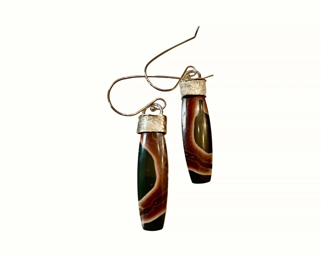 Pair of earrings with brown and dark green cylindrical stones on a white background