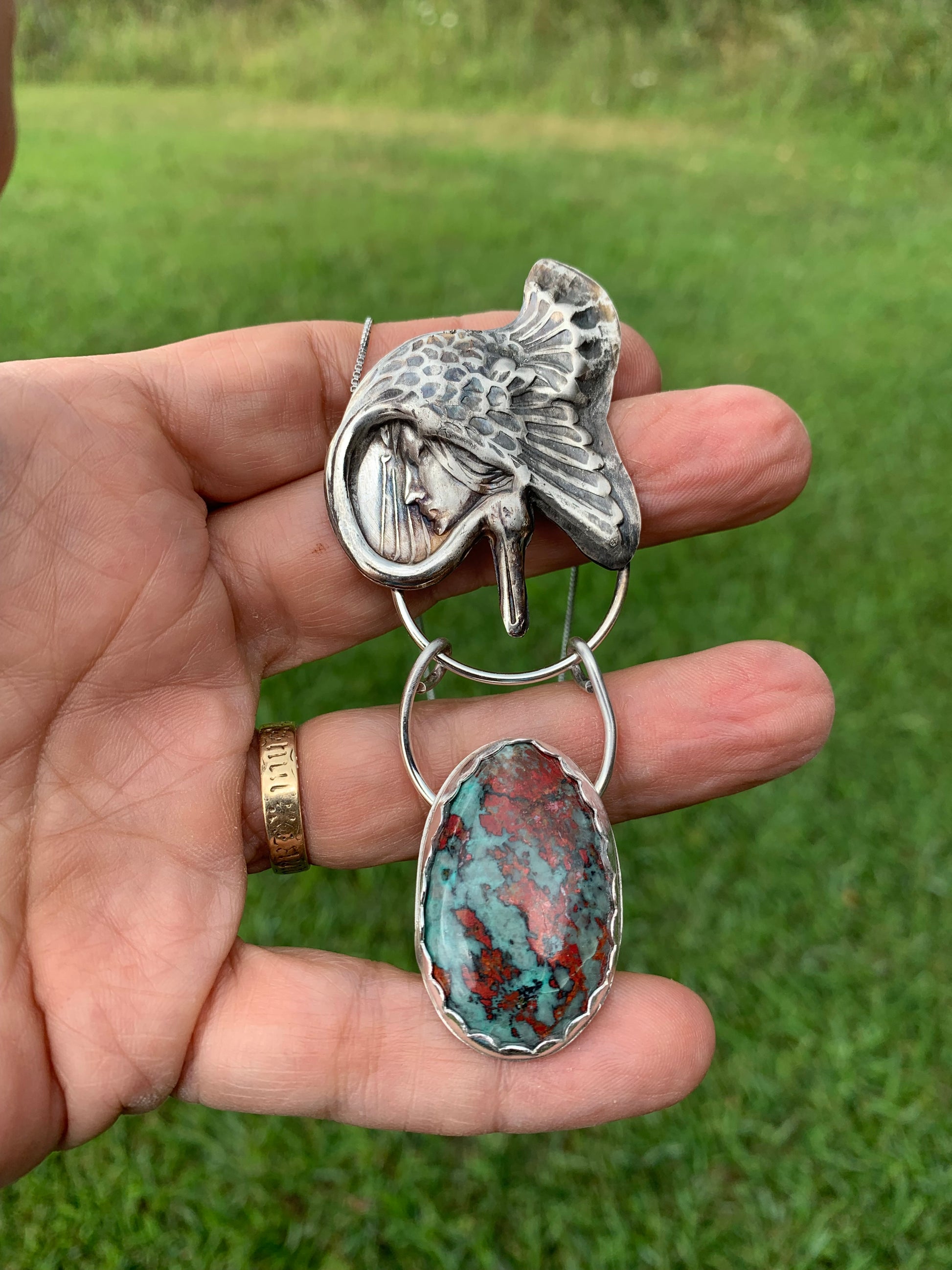 Goddess pendant with turquoise stone, held in hand.