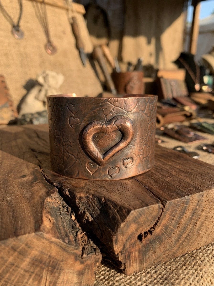 Copper bracelet with heart design on a wooden surface