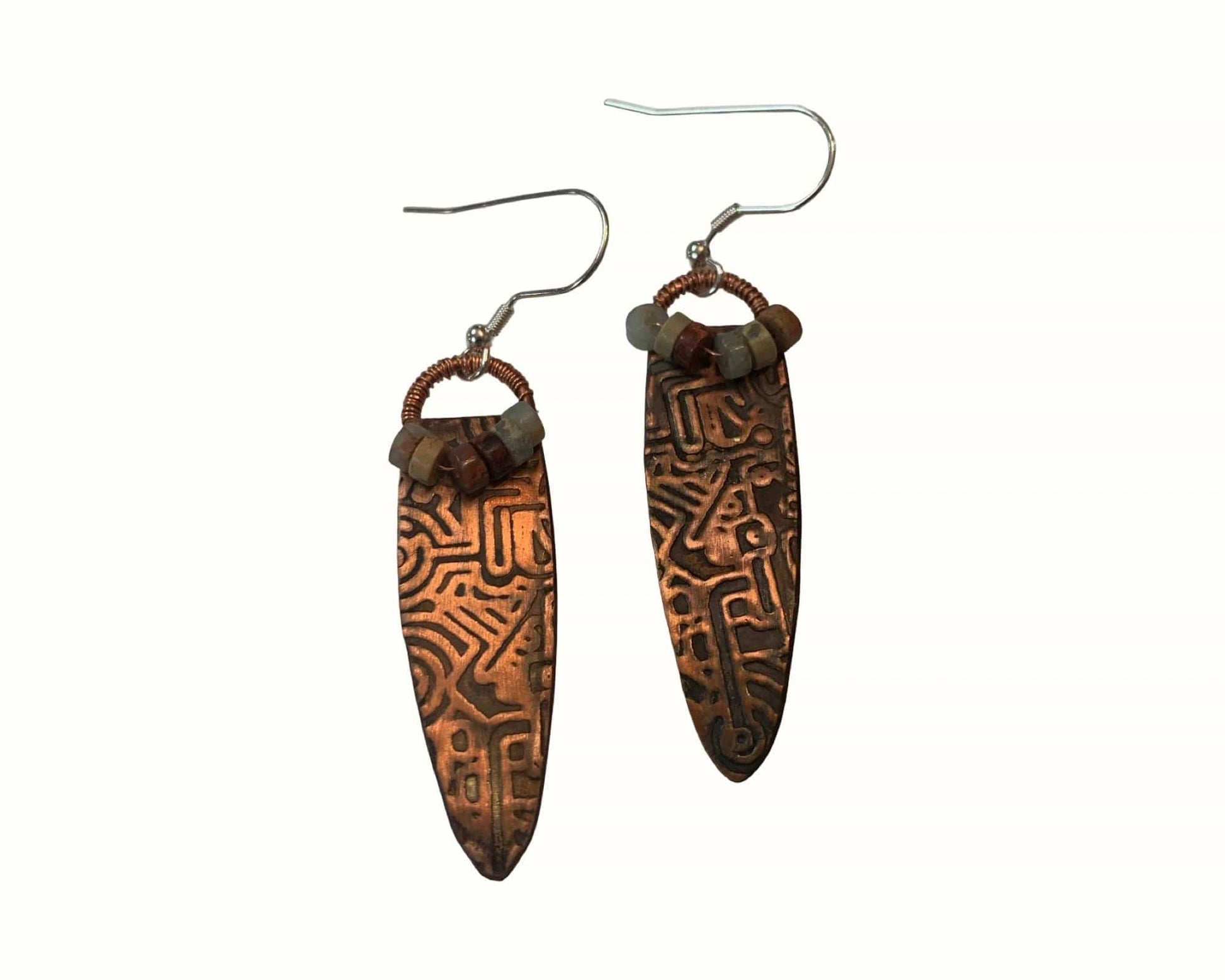 Pair of copper earrings with intricate patterns on a white background