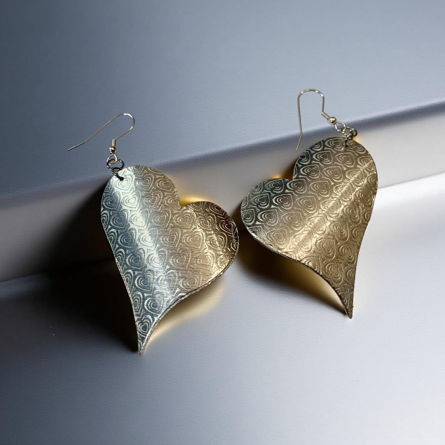 Pair of Aluminum silver patterned earrings on a gray background