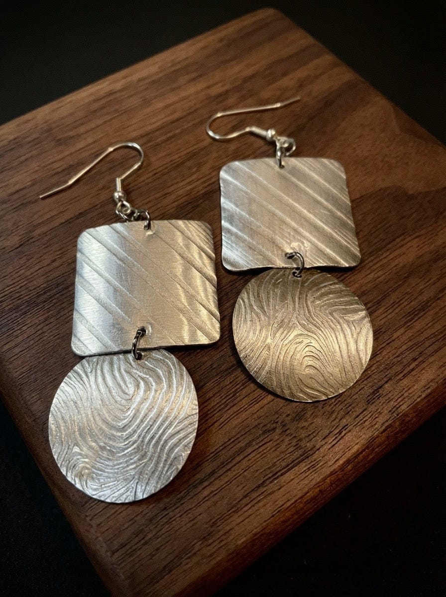 Pair of aluminum earrings on a wooden surface