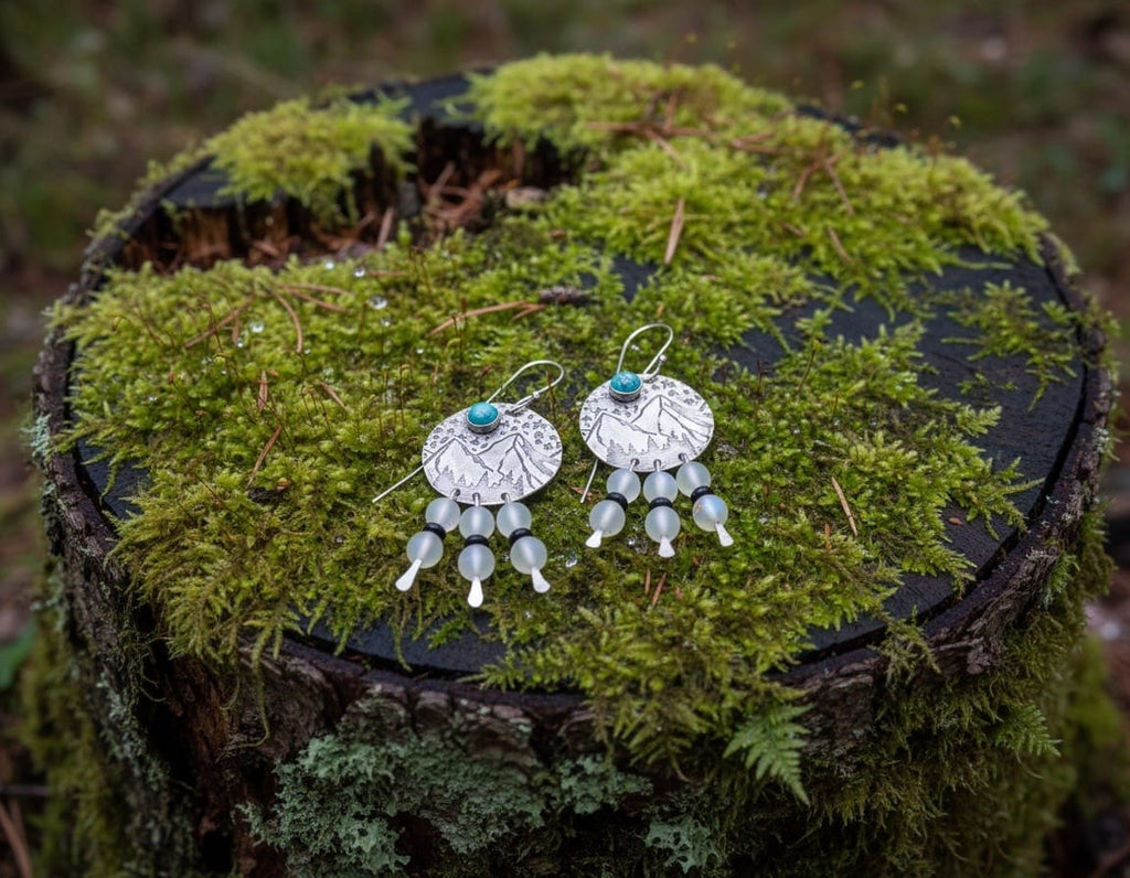 Mountain View handcrafted brass earrings featuring engraved mountain landscapes with genuine turquoise, aurora glass bead dangles, black onyx accents, and sterling silver ear wires.