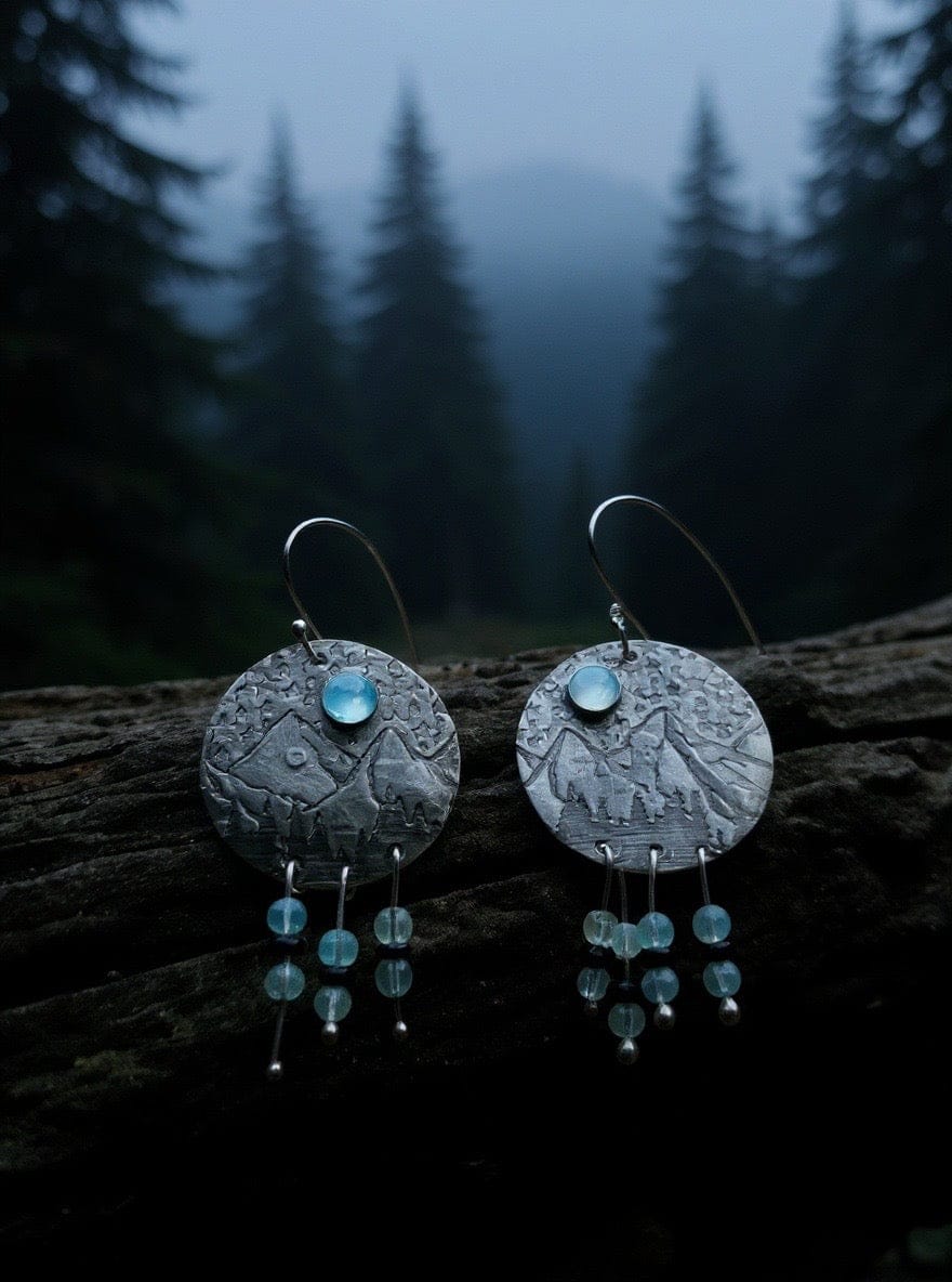 Pair of silver earrings with blue stones on a dark forest background