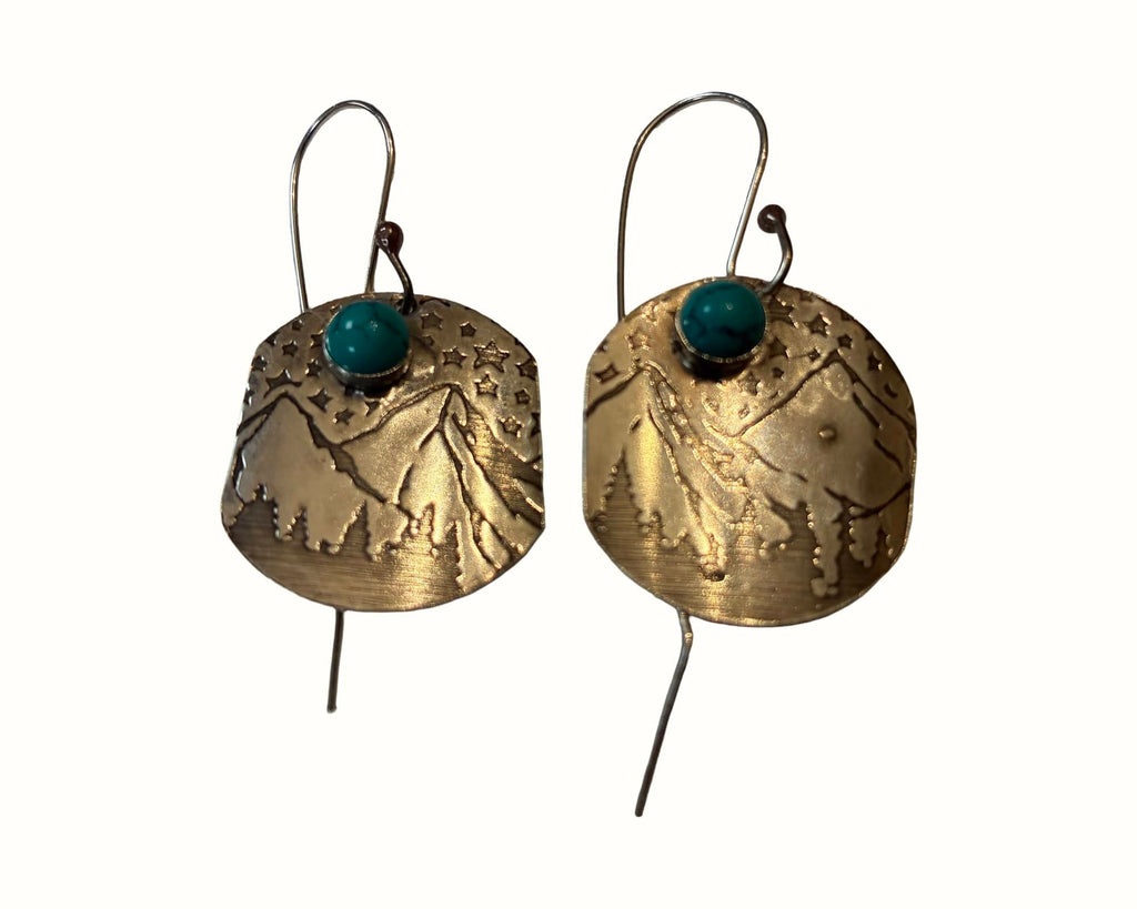 Handcrafted sterling silver Mountain Majesty earrings featuring engraved mountain landscapes beneath a star-filled sky with genuine turquoise cabochons.