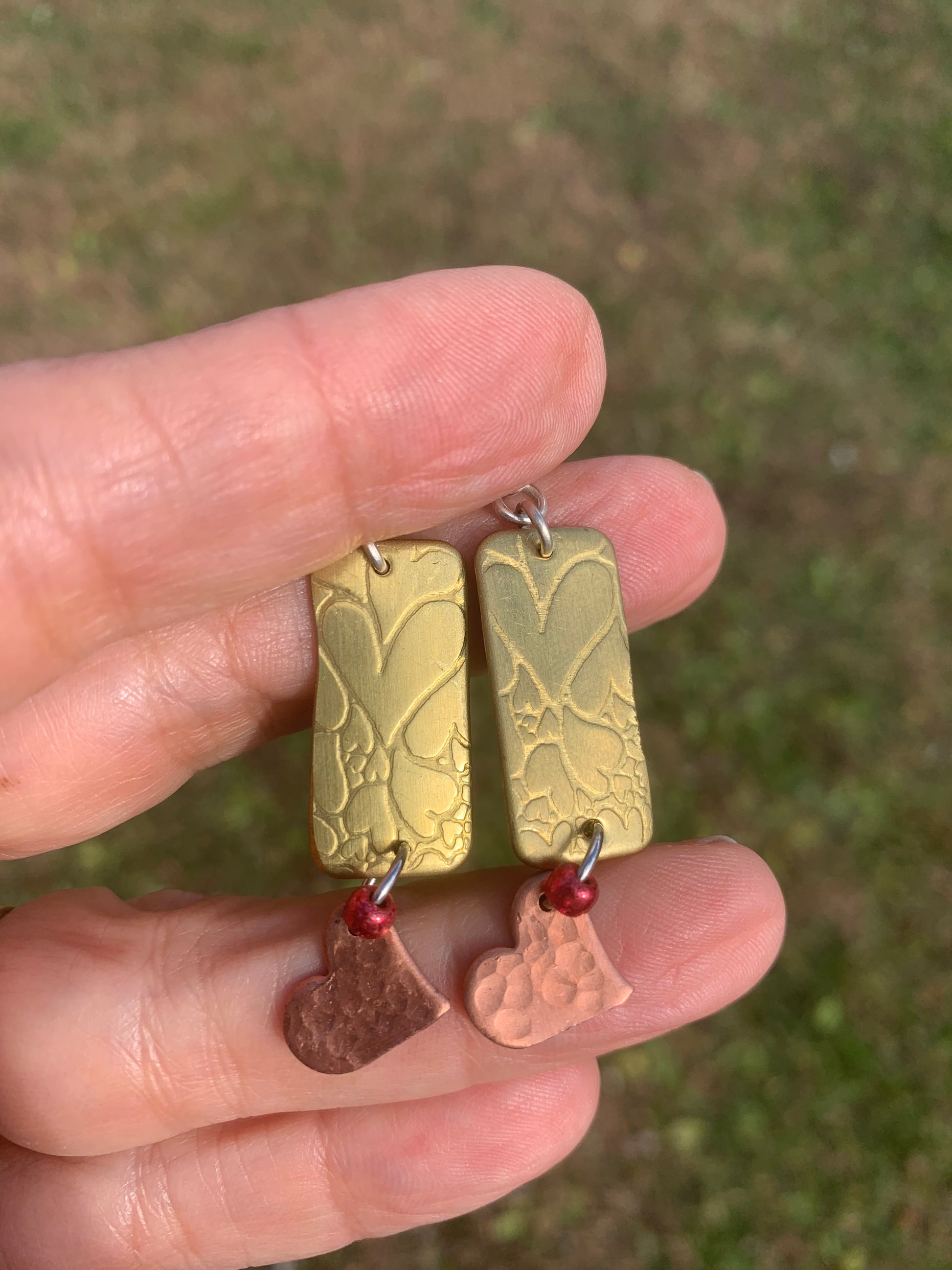Hand Holding earrings made of Brass and Copper with heart designs