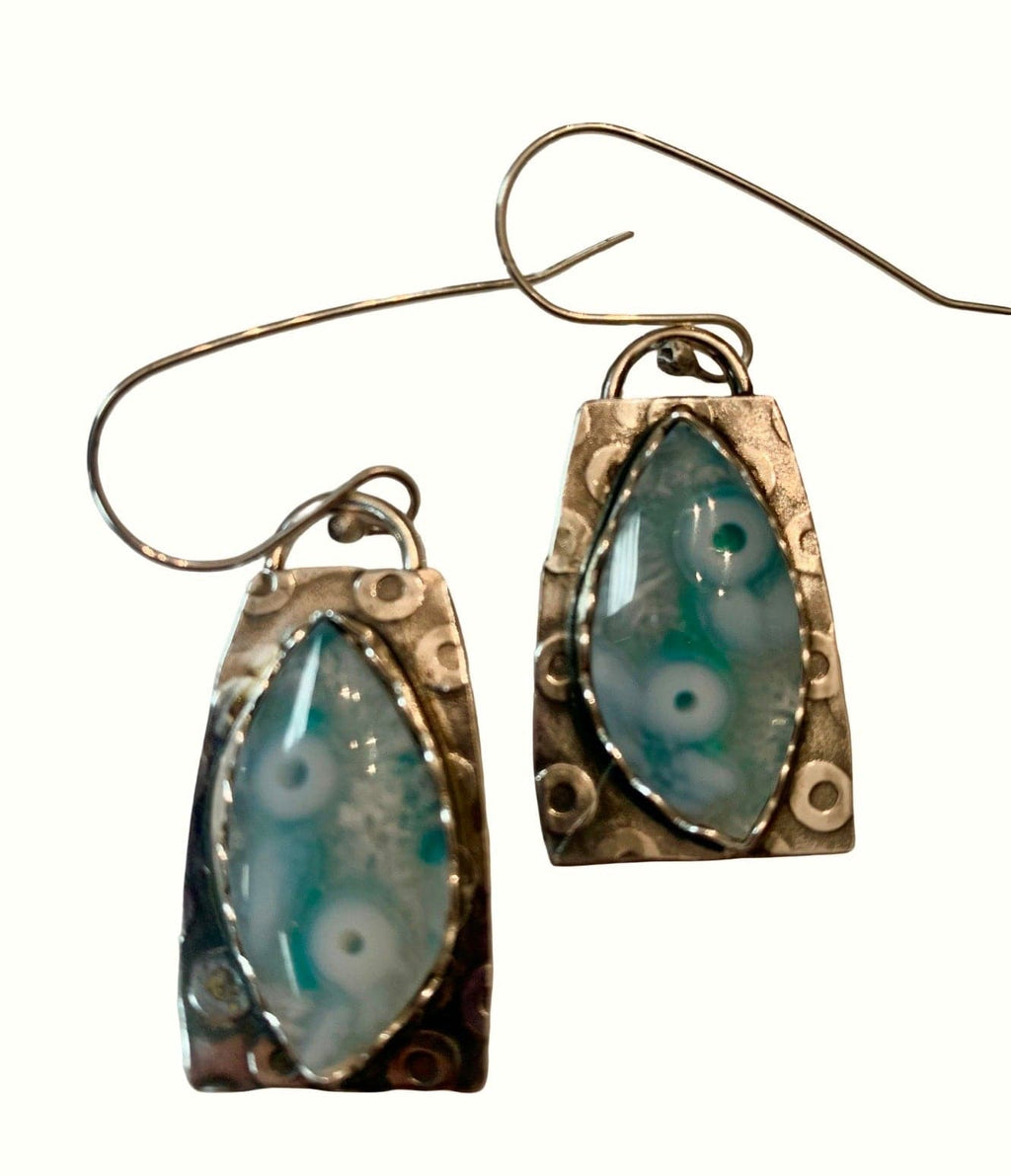 Pair of earrings with blue and white marbled stones in silver frames on a white background