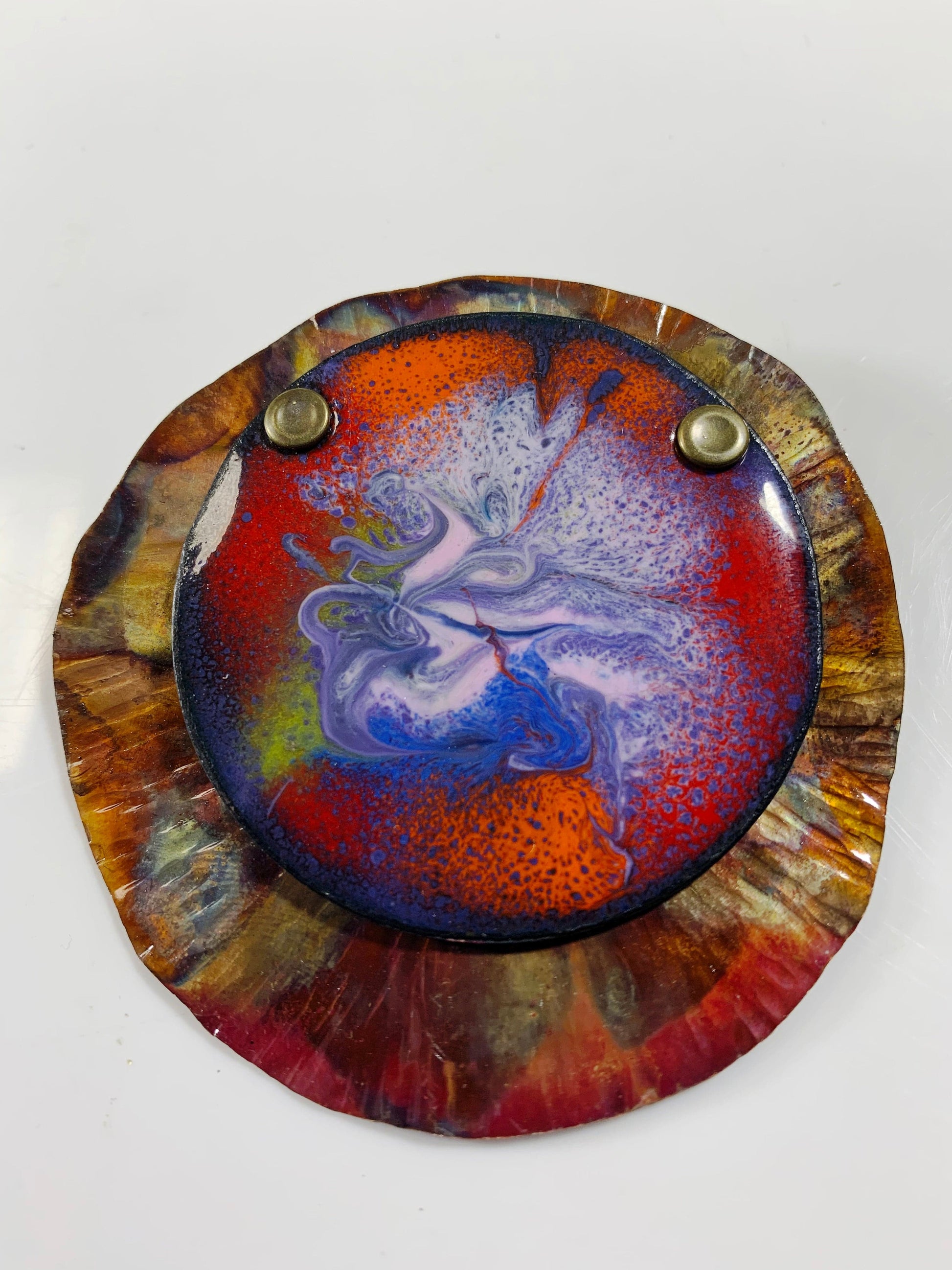 Outer Reaches enamel brooch in a colorful design, red, orange, blue, and gold.