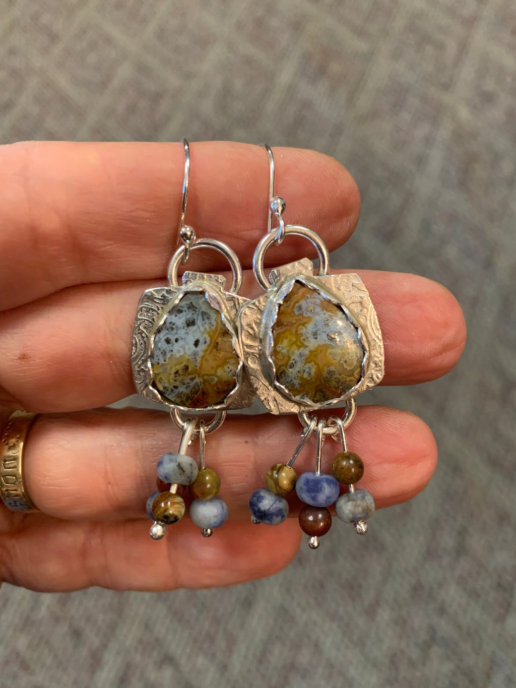 Set of stone earrings held in a hand against a neutral background