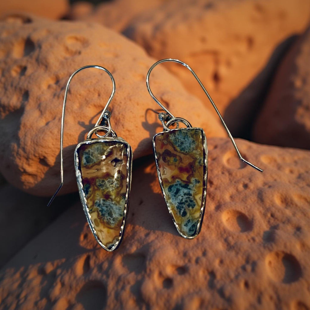 Pair of earrings with multicolored stone-like design on a textured surface
