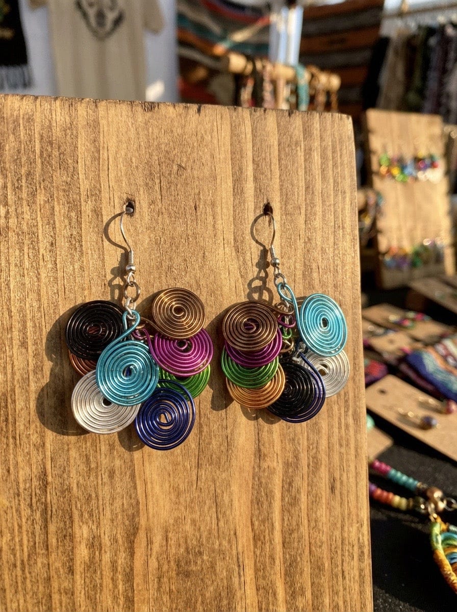 Colorful spiral Aluminum earrings on a wooden stand with a market background