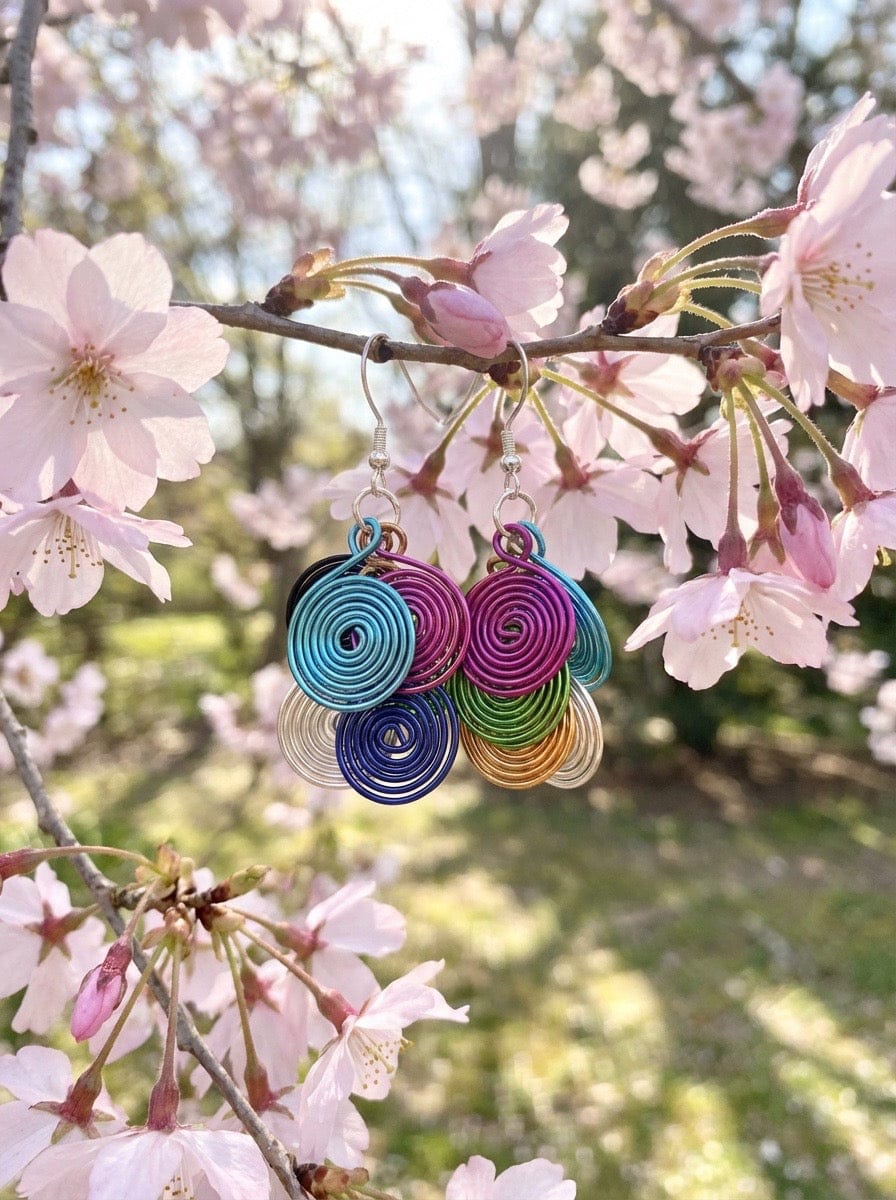 Colorful  Aluminum earrings displayed against a cherry blossom background