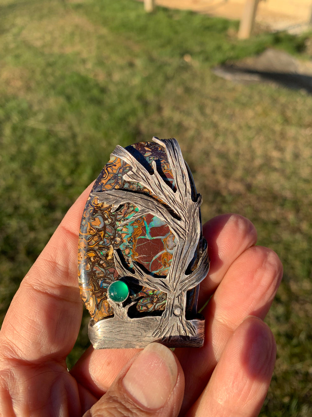 Close-up of Lightning Strikes Boulder Opal with hand-cut sterling silver tree and Green Onyx