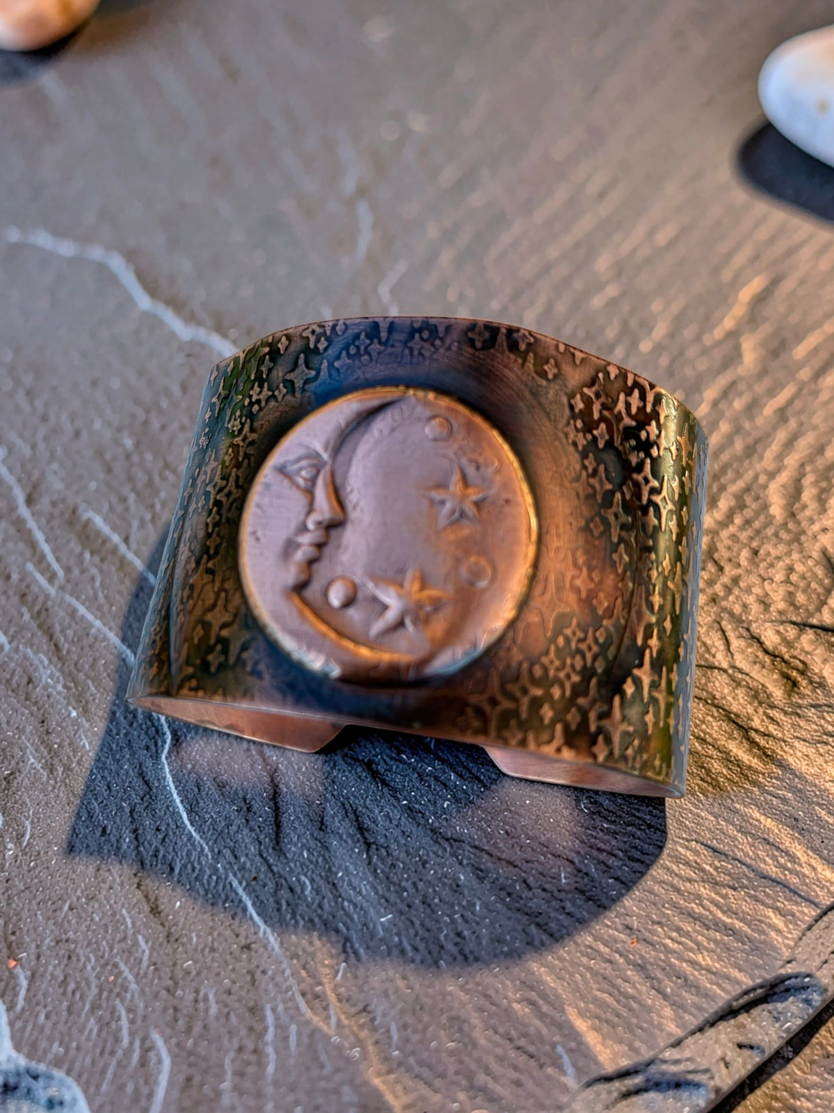 Whispers of the Moon handcrafted copper cuff bracelet by Christine Keller, featuring a moon face and stars with richly textured copper and dark patina.