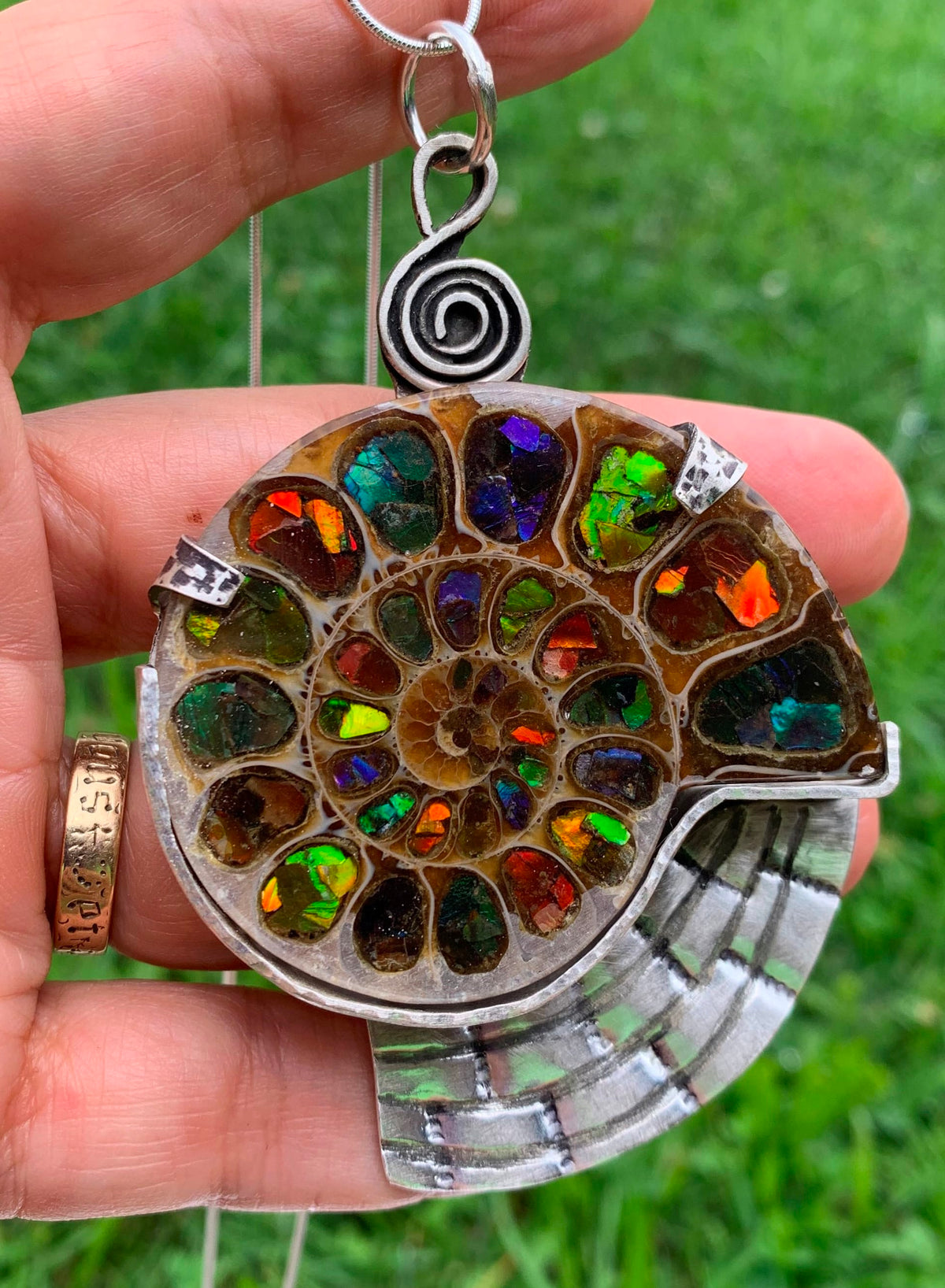 Somewhere ammonite fossil inlaid with colorful Ammolite and handcrafted in sterling silver by jewelry artist Christine Keller.