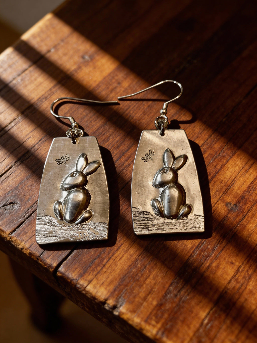 Aluminum rabbit-shaped earrings on a wooden surface