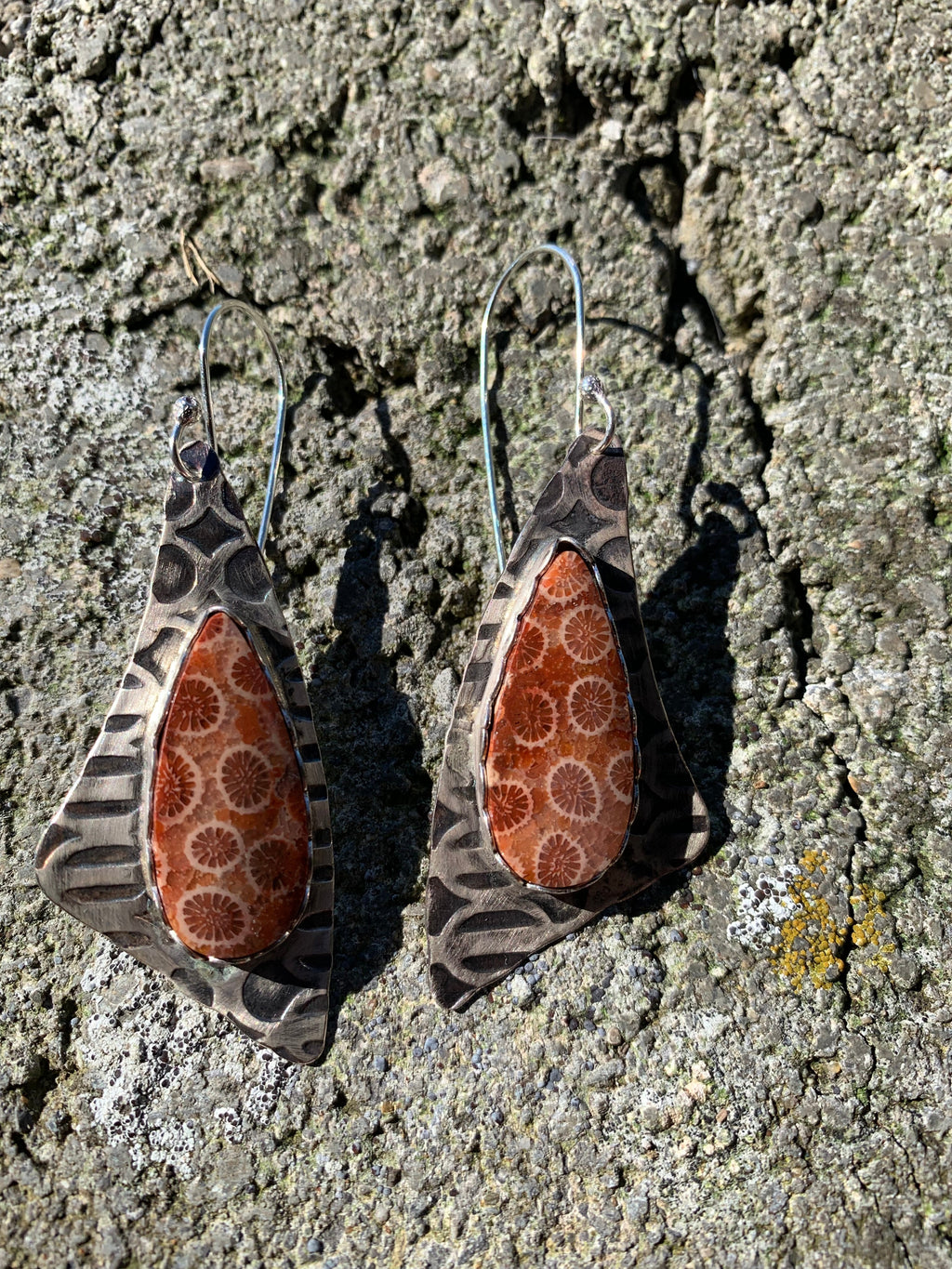 Pair of earrings with brown and white pattern on a textured surface