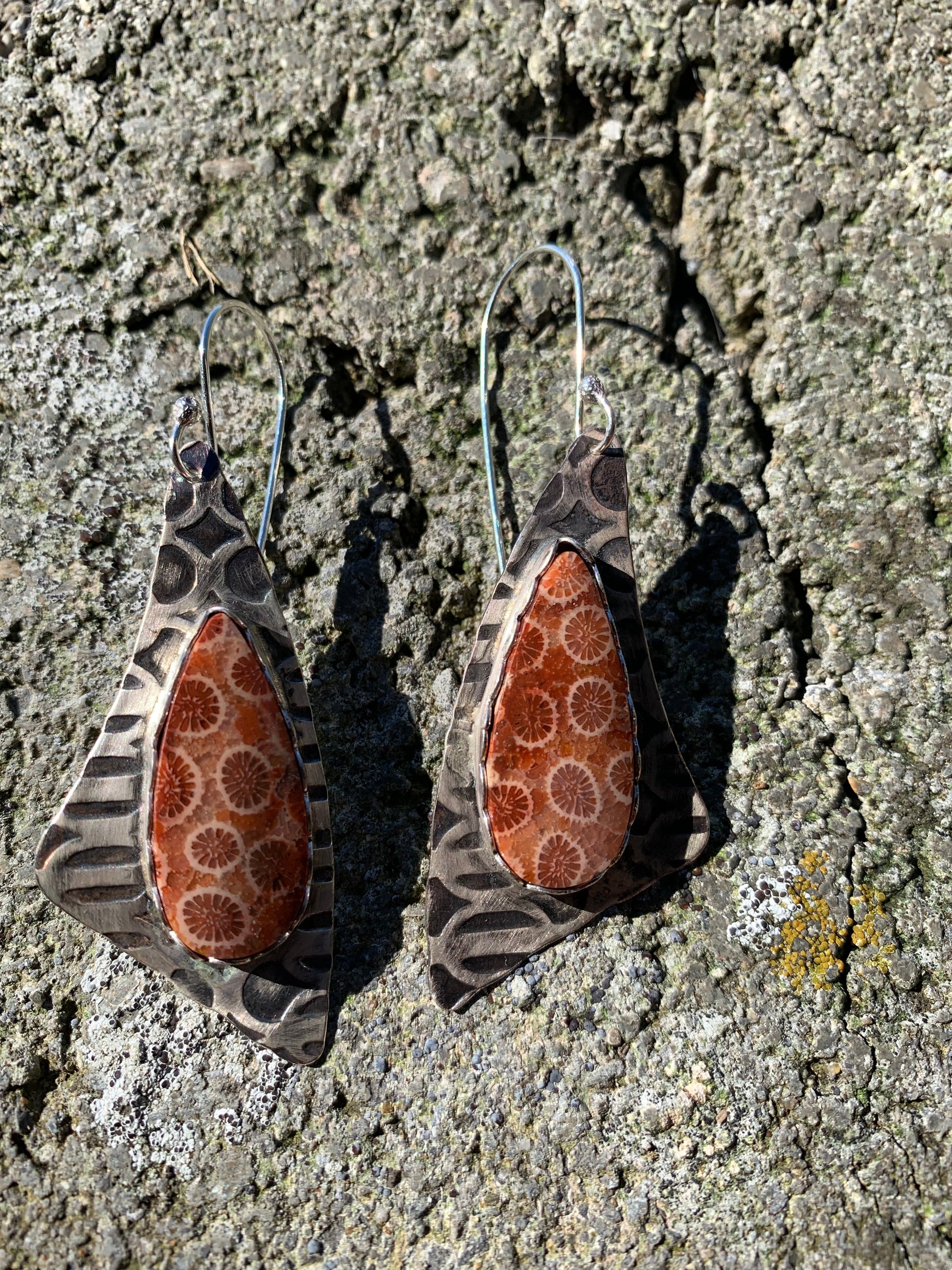 Pair of earrings with brown and white pattern on a textured surface