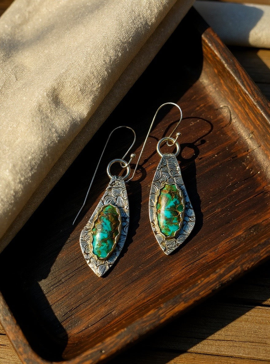 Pair of silver and turquoise earrings on a wooden surface