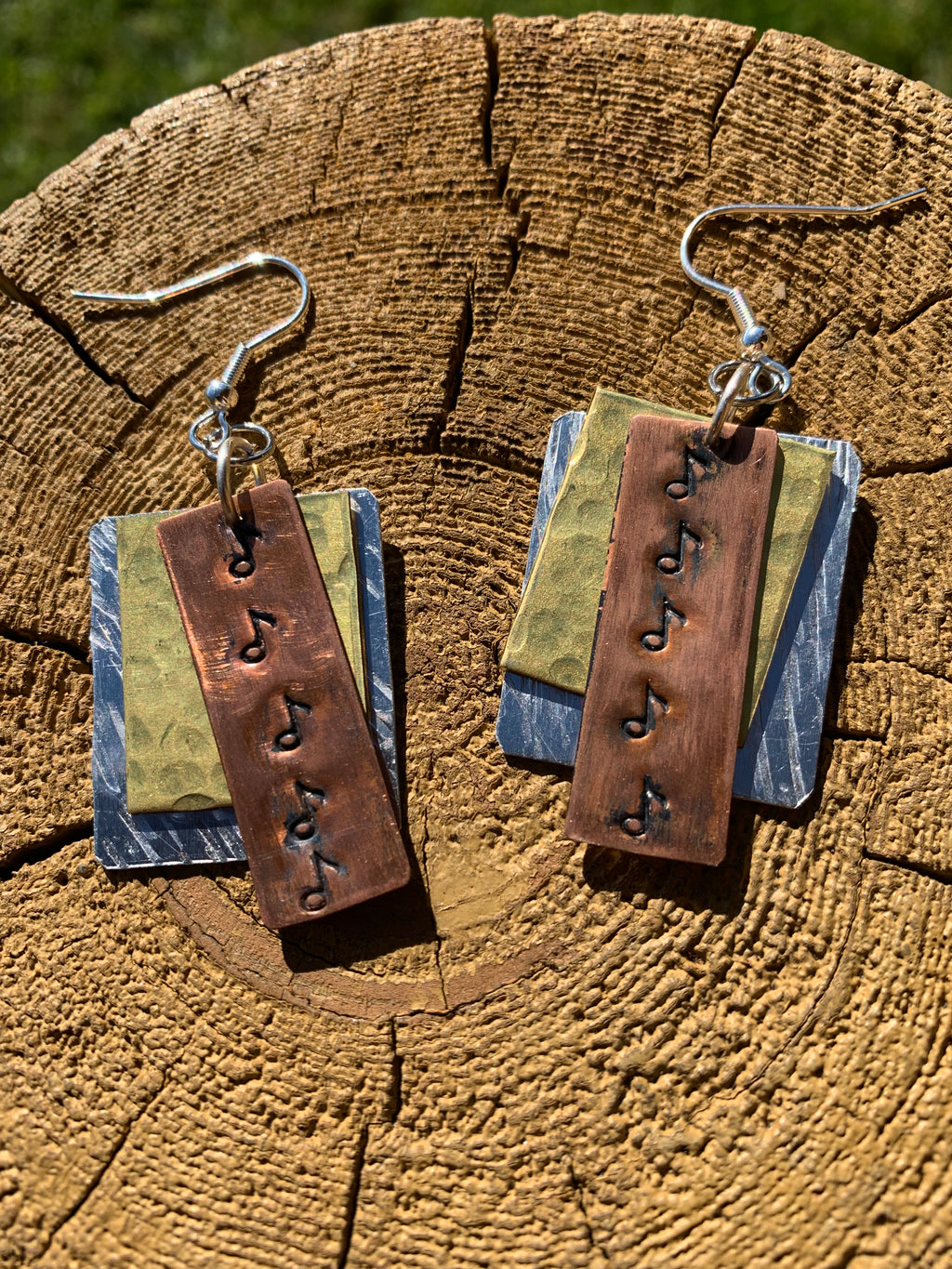 Pair of earrings with copper and music designs on a wooden surface
